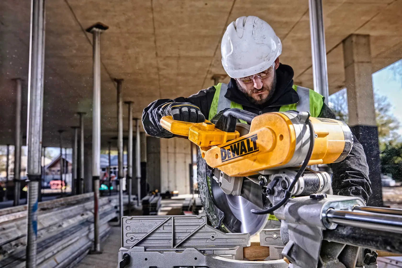 DEWALT DWS780, DWS780KIT saw in use at construction site, worker with helmet and vest. Photography category.