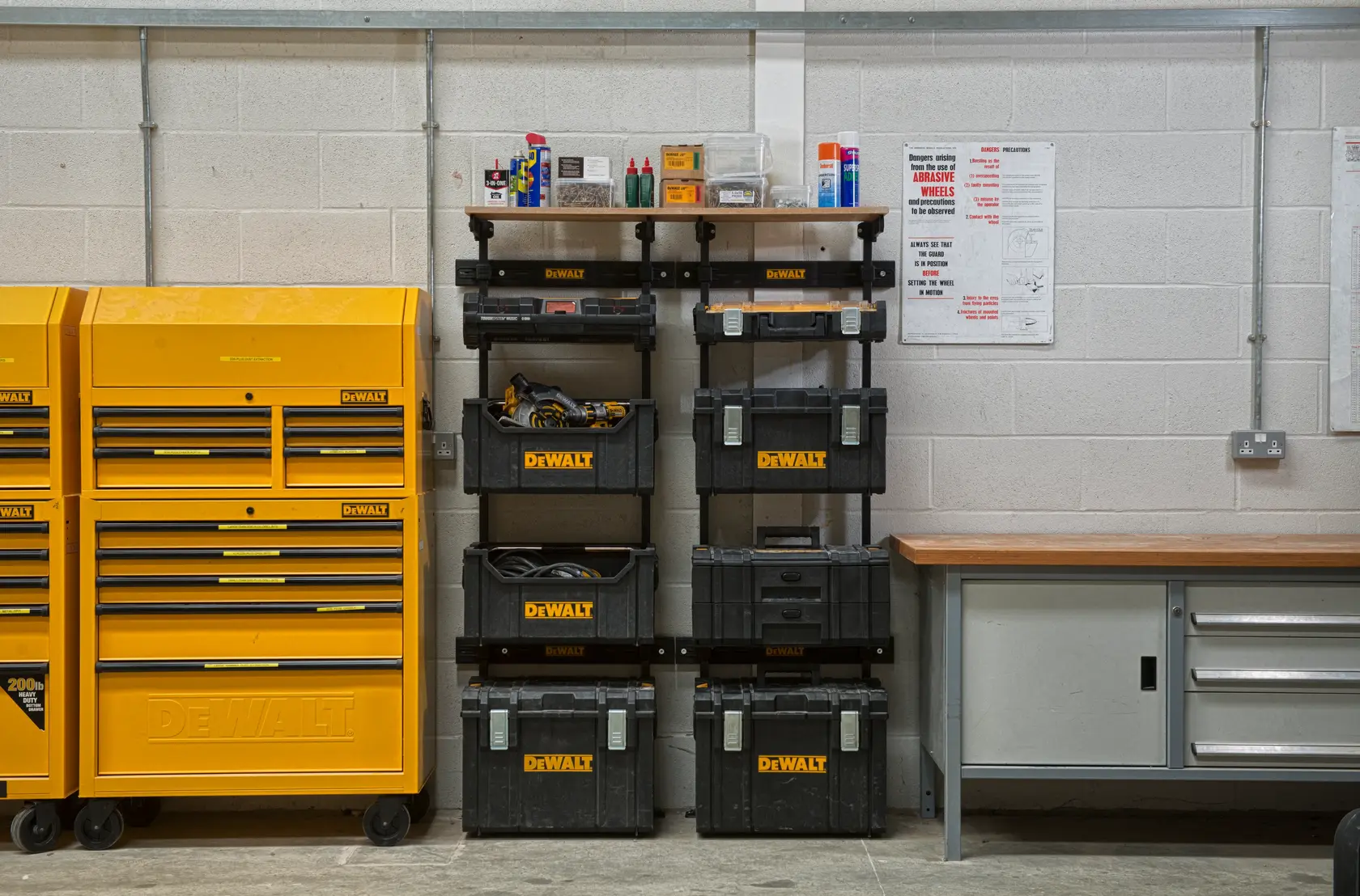 DEWALT toolboxes and storage units organized in a workshop next to a workbench and yellow tool cabinets.